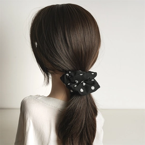 Polka dot hair scrunchie in black and white fabric for elegant low ponytail styling