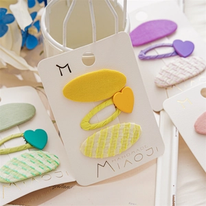 Detailed view of handmade fabric hair clips in heart and oval shapes on a card