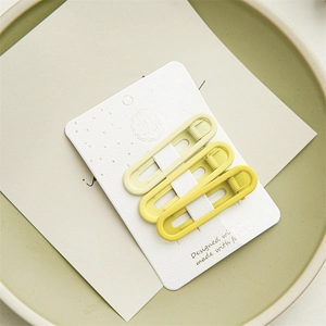 Three-piece yellow gradient hair clips set on a display card and ceramic tray