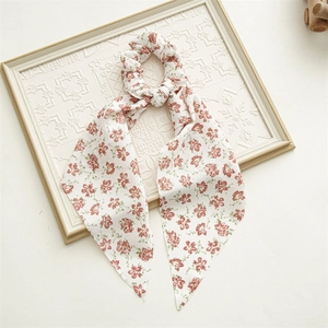 Detail of a beige floral scrunchie with long ribbons on a white vintage frame