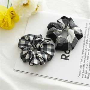 Set of two black and white gingham oversized hair scrunchies on a white magazine background