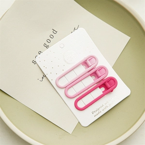 Detailed view of three matte pink gradient hair clips on a card inside a ceramic dish