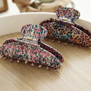 Detailed macro view of acetate hair claws with artistic patterns and metal spring components