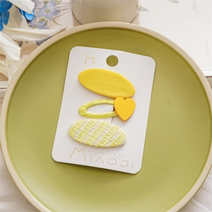 Detail of three-piece yellow hair clips set on card with heart and matte textures