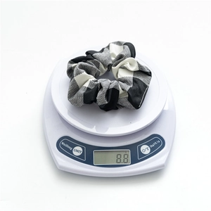 Detail showing a lightweight black and white checkered scrunchie weighing 8.8 grams