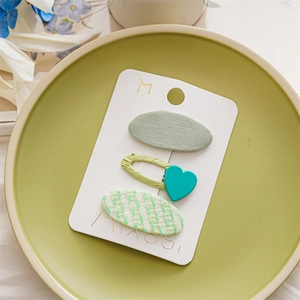 Close-up of light green hair clip set on ceramic plate with heart and stripe details