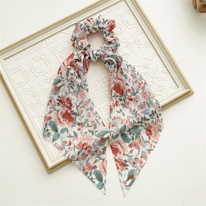 Close-up of floral print scrunchie with long ribbons on vintage white embossed frame