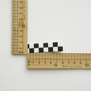 Classic black and white checkered duckbill hair clip measured with a bamboo ruler