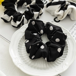 Detail of black and white polka dot scrunchie on decorative plate with striped fabric texture