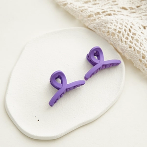 Vue détaillée de deux pinces à cheveux spirales violettes mates sur plat décoratif