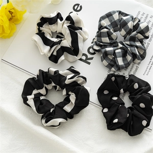 Detailed close-up of four black and white patterned scrunchies on a minimalist background