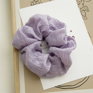 Detail eines hellvioletten Scrunchies aus Faltenstoff mit feiner Textur auf Karte