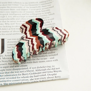 Detail showing the zigzag acetate hair claw clip with vintage wavy patterns and smooth texture
