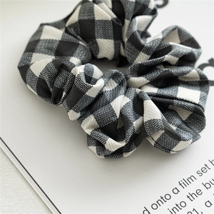Detail of black and white checkered scrunchie with fine ribbed texture on a white page