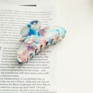 Close-up of large acetate hair claw clip with blue and pink watercolor marble texture