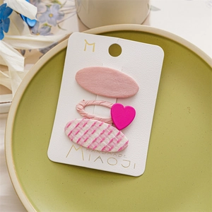 Close-up of pink three-piece girls hair clips set with heart decor on a display card