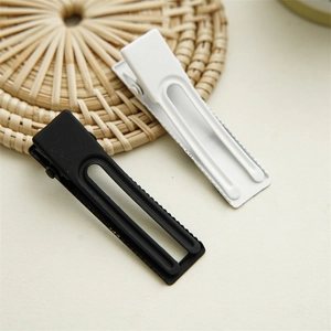 Detail view of black and white checkerboard duckbill hair clips with matte texture