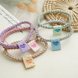 Colorful elastic woven hair ties with sweet square fabric labels in a soft setting