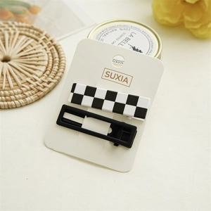 Close-up of checkerboard and black hair clips on a card with cozy lifestyle decor
