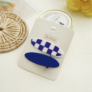 Detail view of blue solid and checkered hair clips on a white paper display card