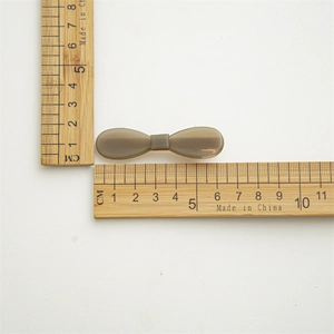 Bow-shaped acetate hair clip in translucent smoky gray with dimensions 4.5cm shown on ruler