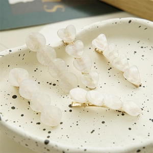 Macro shot of seashell-textured hair clips in heart and geometric shapes with gold metal base