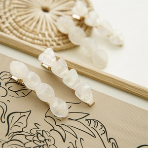 Close-up of geometric iridescent shell hair clip with marble acrylic and gold metal base