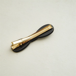 Detailed back view of a golden alligator clip with black base and serrated grip teeth