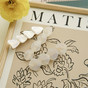 Detail of iridescent geometric shell hair clips with golden metal base on beige background