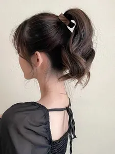 Détail d'une pince à cheveux spirale marron fixant une queue de cheval haute sur un modèle