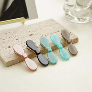 Set of five colorful acetic acid bow hair clips on a premium stone display board