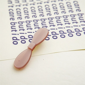 Close-up of matte pink acetate hair clip with golden metal base on minimalist background