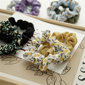 Gros plan de chouchous à fleurs et unis sur plateau en bois avec texture de tissu