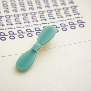 Close-up of mint green acetate bow hair clip with matte finish and gold metal base