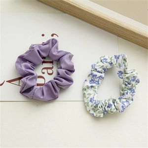Détail d'un ensemble de chouchous fleuris et violets sur fond beige avec décoration