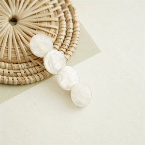 Close-up of four pearlescent marble-textured circular discs on a metal hair clip
