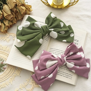 Vintage polka dot fabric bow hair clips in green and purple colors on a retro book