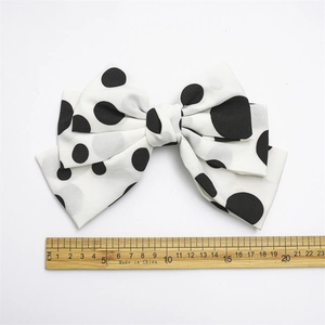 Macro detail of large polka dot fabric bow clip measuring approximately 17.5 cm in width
