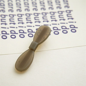 Macro shot of a charcoal grey acetate bow hair clip showing smooth matte texture