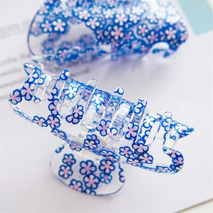 Detailed close-up of acrylic hair claw clip with colorful floral pattern on bright magazine
