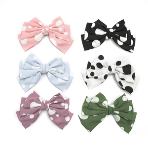 Close-up of colorful polka dot bow hair clips in pink black and blue fabric