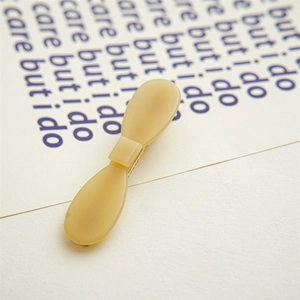 Close-up of minimalist cream yellow acetic acid hair clip with matte texture on printed paper