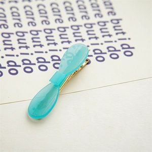Detail of light blue acetate bow hair clip with golden metal duckbill structure