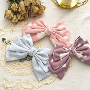 Close-up of three layered polka dot fabric hair bows in pink, blue and purple on lace