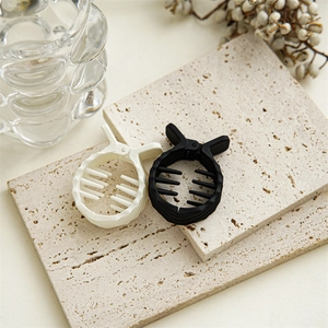 Mini pinces à cheveux mates noires et blanc crème sur plaque de pierre beige