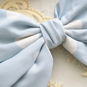 Detail of light blue polka dot fabric bow hair clip showing elegant texture and pattern