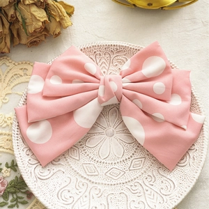 Detail of multi-layered pink polka dot bow hair clip on a vintage decorative white plate