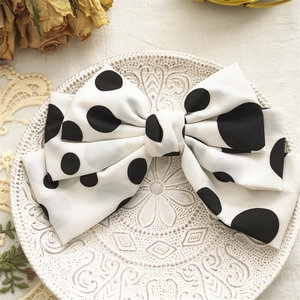 Detail of a white polka dot chiffon bow hair clip on an elegant vintage ceramic plate