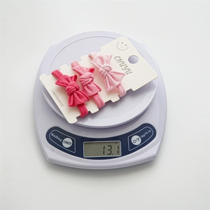 Detailed view of three elastic bow hair ties weighing 13.1g on a digital scale