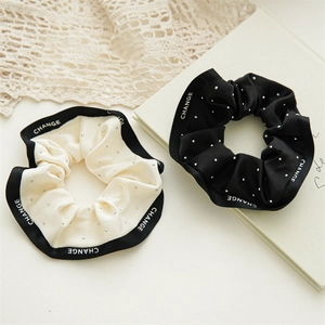 Détail de chouchous en satin avec strass et motif CHANGE sur le bord du tissu
